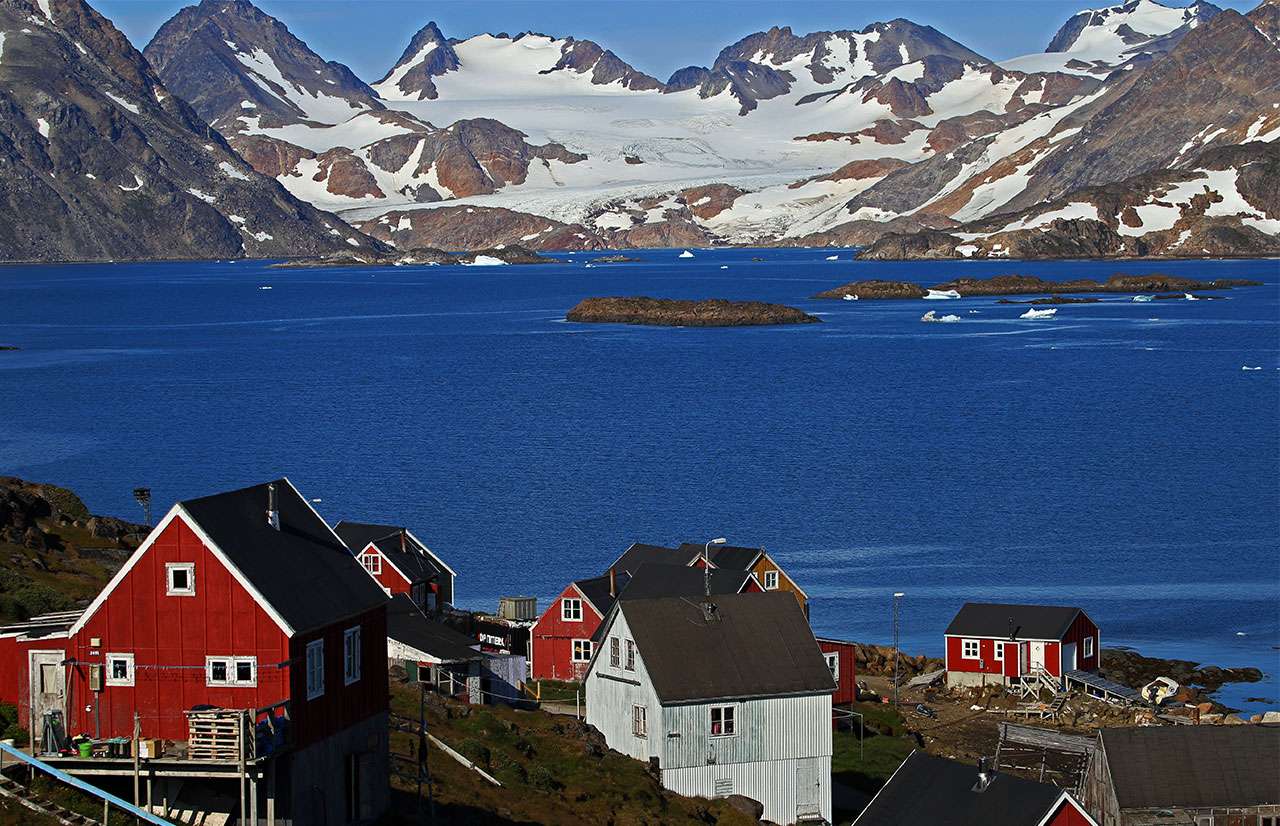 Groenlandia-Orientale-vista sul paese di kulusuk con le tipiche casetteolorate, il mare e le montagne innevate