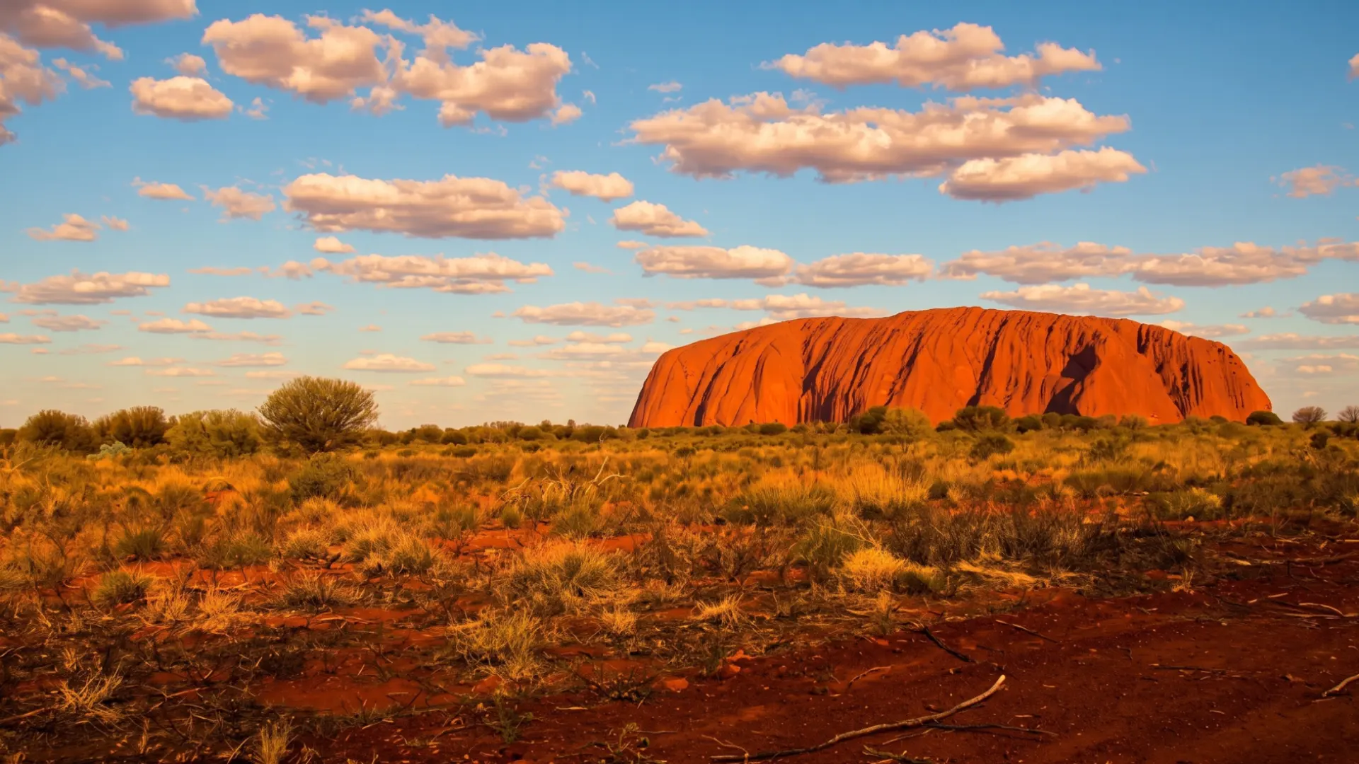 Paesaggio dell’Outback australiano con grande formazione rocciosa rossa legata alla cultura aborigena e al Dreamtime